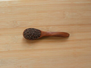 Black color whole Mustard seeds on wooden spoon