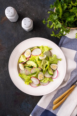 Diet vegetables salad with cucumbers, quaill eggs and radish on a white plate. Top view.
