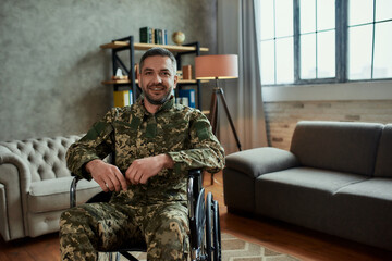 Recovery. Middle aged male military in a wheelchair looking at camera with a smile, during therapy session. Disabled soldier suffering from depression, psychological trauma. PTSD concept - obrazy, fototapety, plakaty