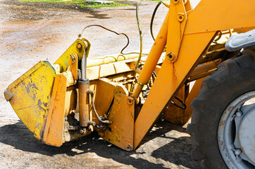 the empty dirty bucket of a small tractor lies on the pavement. The concept of repair, house...
