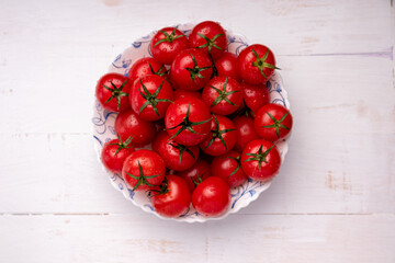 red cherry tomatoes in a bowl on a wooden background