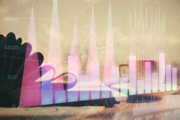 Double exposure of financial chart drawing and desktop with coffee and items on table background. Concept of forex market trading