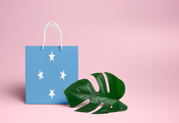 Micronesia shopping concept. National cardboard shopping bag with monstera leaf and pink background. Online shopping theme.