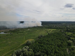 Fire and white smoke with green summer landscape