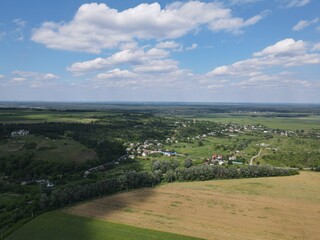 Aerial view of yellow and green fields in summer with blue sky and white clouds