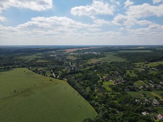 Aerial view of yellow and green fields in summer with blue sky and white clouds