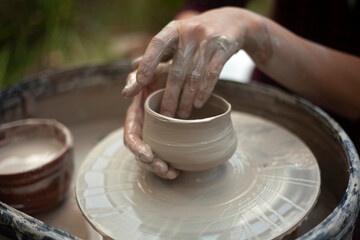Potter at work. Hands sculpt clay. Creation of dishes.