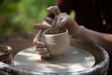 Potter at work. Hands sculpt clay. Creation of dishes.