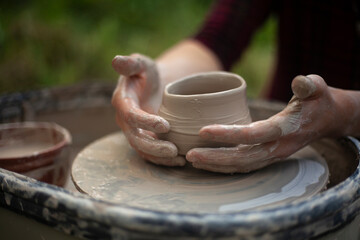 Potter at work. Hands sculpt clay. Creation of dishes.