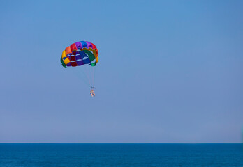 Fototapeta na wymiar Parasailing, also known as parascending or parakiting, is a recreational kiting activity where a person is towed behind a vehicle (usually a boat) while attached to a specially designed canopy wing