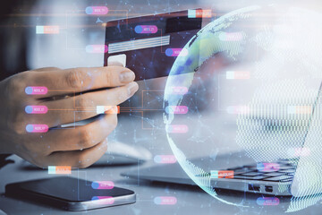Double exposure of woman on-line shopping holding a credit card and world map hologram drawing. International E-commerce concept.