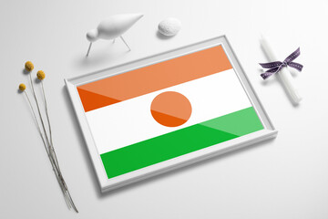 Niger flag in wooden frame on table. White natural soft concept, national celebration theme.