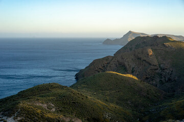 Fototapeta na wymiar Scenic view of cliffs by seascape against clear sky at sunset