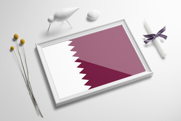 Qatar flag in wooden frame on table. White natural soft concept, national celebration theme.