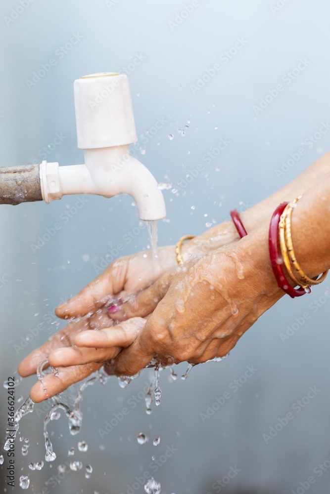 Poster Female washing hands under the faucet - importance of washing hands during the COVID-19 pandemic