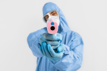doctor in a protective suit against coronavirus, a surgical mask, gloves and glasses, using an...