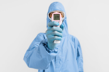 doctor in a protective suit against coronavirus, a surgical mask, gloves and glasses, using an...