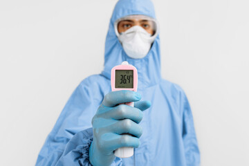 male doctor in a protective suit from the coronavirus, a medical mask glasses and gloves, uses an...