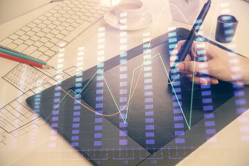 Double exposure of financial graph sketch hologram and woman holding and using a mobile device. Stock exchange concept.