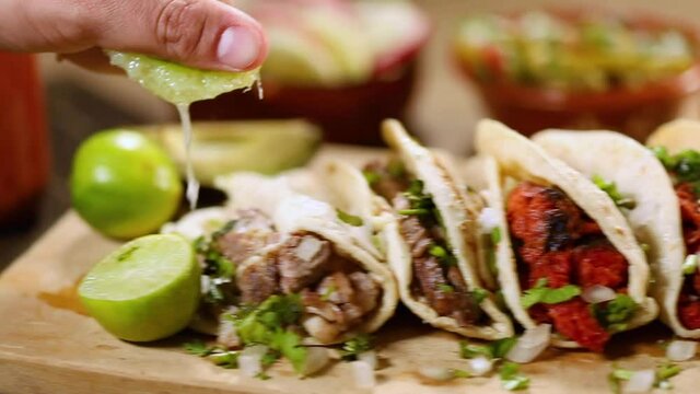 Close up shot of some delicious tacos. Man putting lemon juice