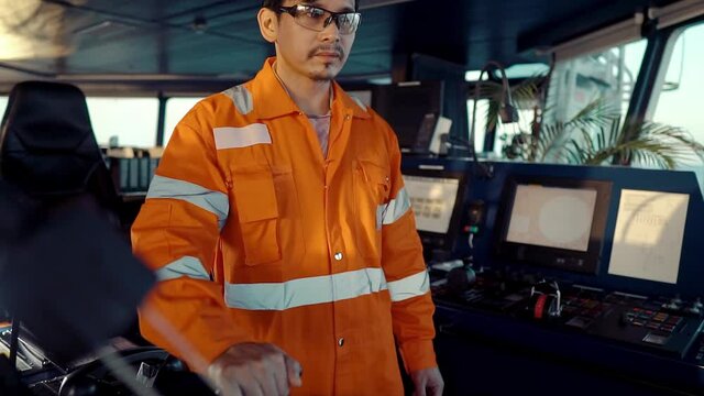 Filipino deck Officer on bridge of vessel or ship wearing coverall during navigaton watch at sea . He is maneuvering with cpp thrusters propulsion