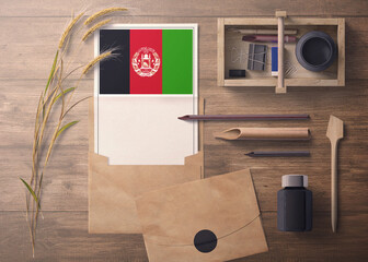Afghanistan invitation, celebration letter concept. Flag with craft paper and envelope. Retro theme with divide, ink, wooden pen objects.