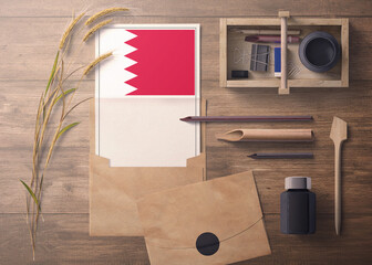 Bahrain invitation, celebration letter concept. Flag with craft paper and envelope. Retro theme with divide, ink, wooden pen objects.