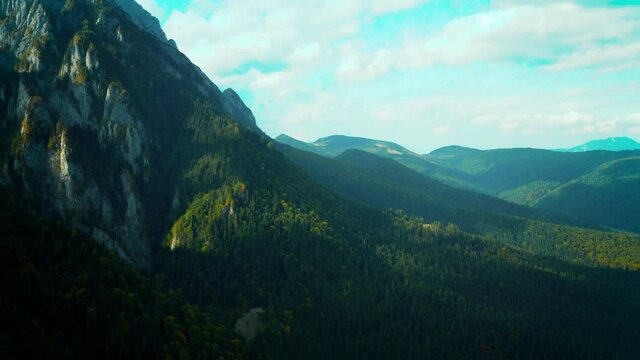 Aerial panoramic view of rocky mountains range near the city Busteni. Video from drone flying over forested and cliffs slopes of Carpathian Mountains range. Majestic landscape in Romania, travel, 4k