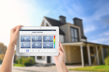 Energy efficiency home control system. Woman using tablet to set temperature in different rooms, closeup