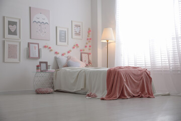 Modern teenager's room interior with comfortable bed and beautiful pictures