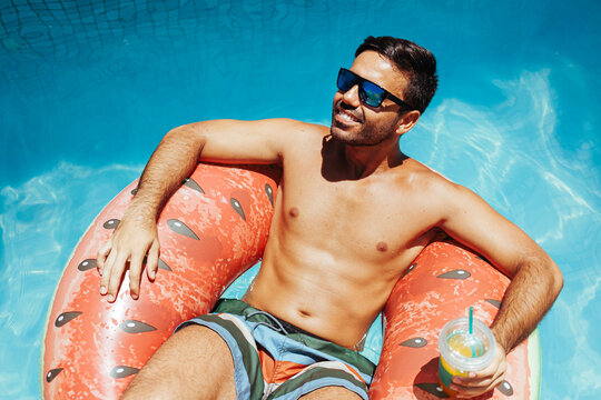 Handsome Man Relaxing Alone On A Float In The Pool On A Hot Summer Day