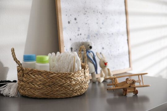 Wicker basket with accessories and wooden airplane on grey table in child room