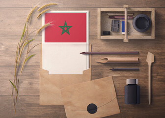 Morocco invitation, celebration letter concept. Flag with craft paper and envelope. Retro theme with divide, ink, wooden pen objects.