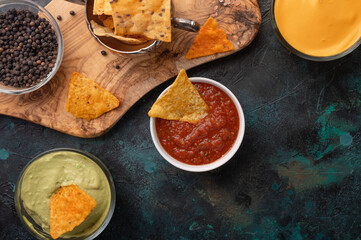 Various snacks and chips for a party on a blue background with salsa and sauces