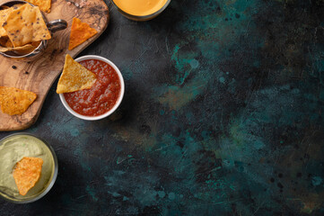 Various snacks and chips for a party on a blue background with salsa and sauces