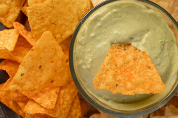 Chips and snacks with avocado and dip sauce, close-up top view