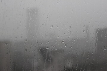 Natural Pattern of raindrops isolated on cloudy background. Rainy day. Raindrops on window glass. Close up shot on droplets of the rain on window glass.