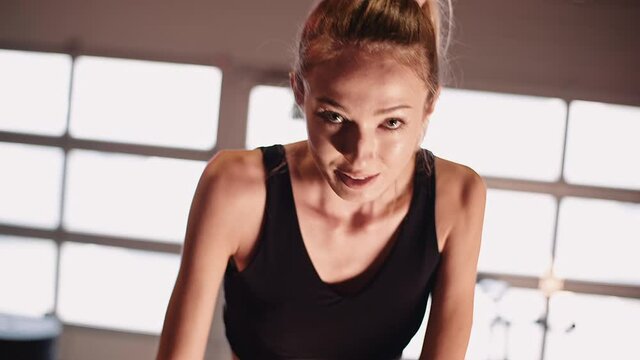 Young Fit Sporty Blone Girl Exercising on a Bike at Gym