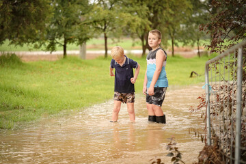 Boys playing in flooded creek with wet gumboots