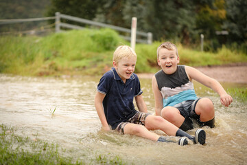 Fototapeta premium Happy kids playing in floodwater on rainy day