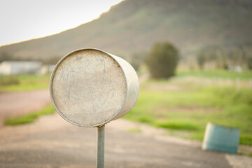 Round metal mailbox on country road with mountain in background