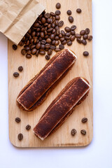 Top view on eclairs to wooden board with sprinkled coffee beans.