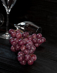 Bunch of red grapes and champagne glass with dark wood background