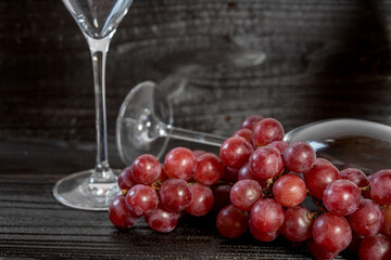 Red grapes and champagne glasses with rustic wood background