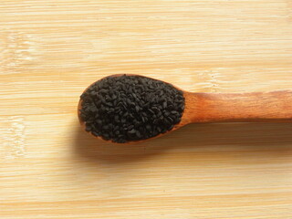 Black caraway or Nigella sativa seeds on wooden spoon