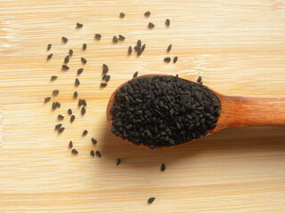 Black caraway or Nigella sativa seeds on wooden spoon