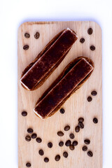 Top view on eclairs to wooden board with sprinkled coffee beans.