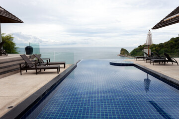 Fototapeta na wymiar Swimming pool overlooking view andaman sea and clear sky background,summer holiday background concept.