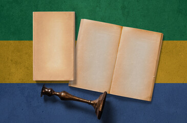 Gabon vintage historical concept. Retro craft papers and old wooden candlestick on national flag wall background.
