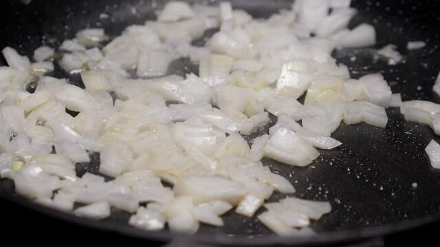 Frying onion on pan. Cooking dinner. Closeup. Nobody